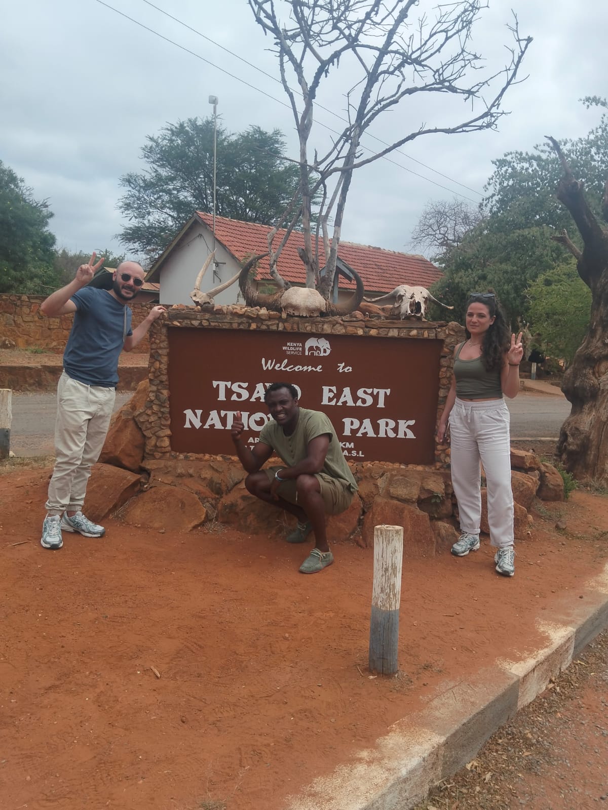 Viaggiatori davanti al cartello del Parco Nazionale Tsavo Est